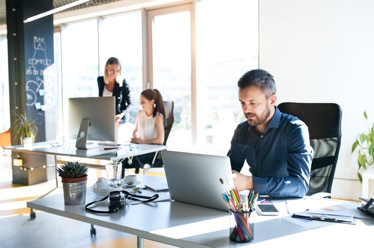 man-sat-at-desk-infront-of-laptop