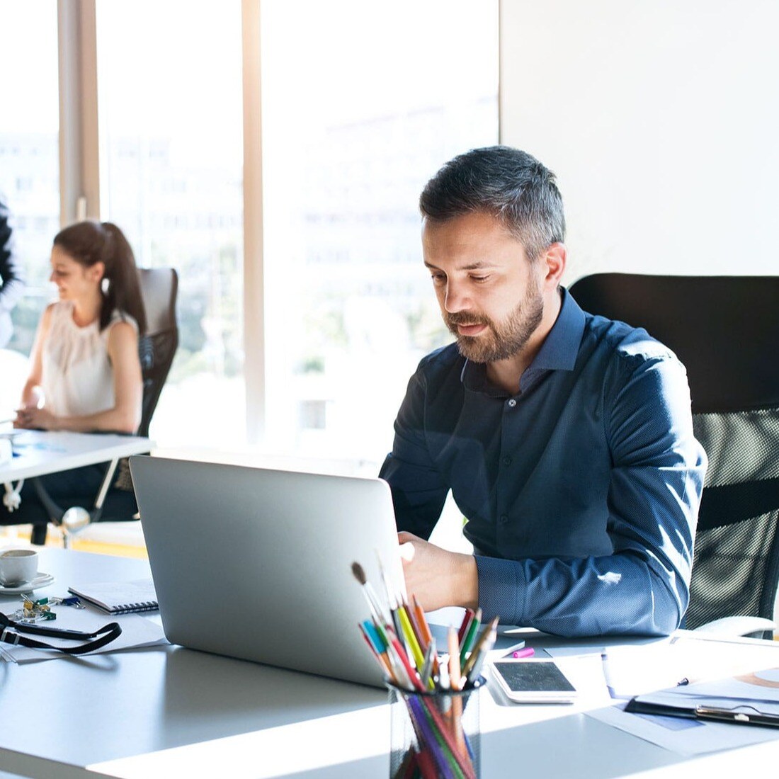 man-sat-at-desk-infront-of-laptop